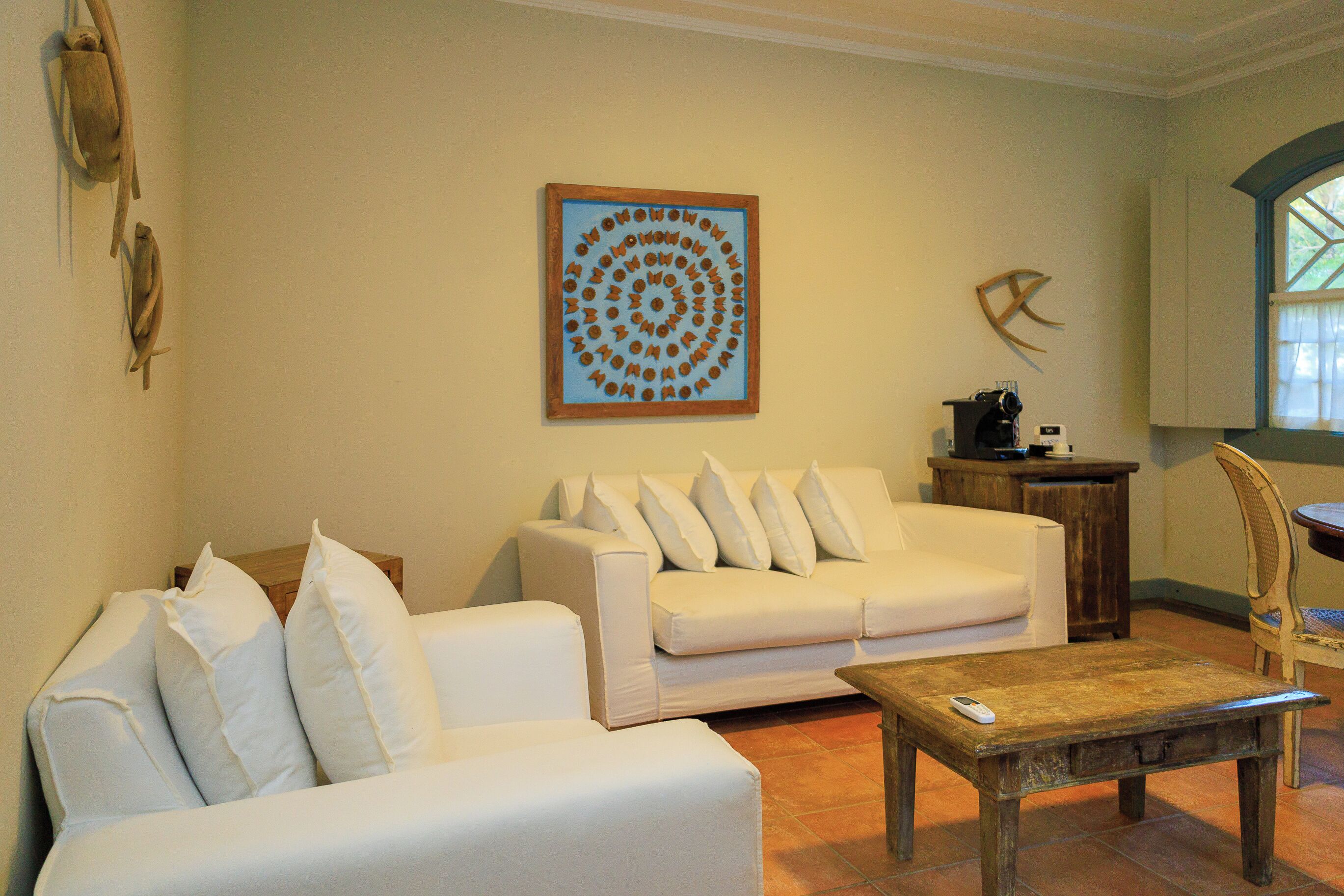 Een woonkamer met een witte bank, een houten salontafel en een kunstwerk aan de muur.
