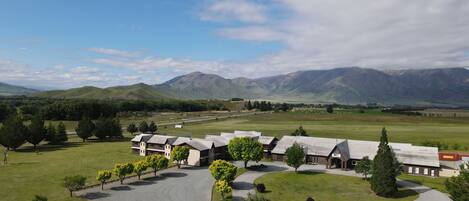 A hotel with a central courtyard, surrounded by a lush green landscape and mountains in the background.