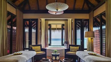 Enjoy a serene ocean view from the large window, accompanied by a comfortable seating area and a relaxing massage table.