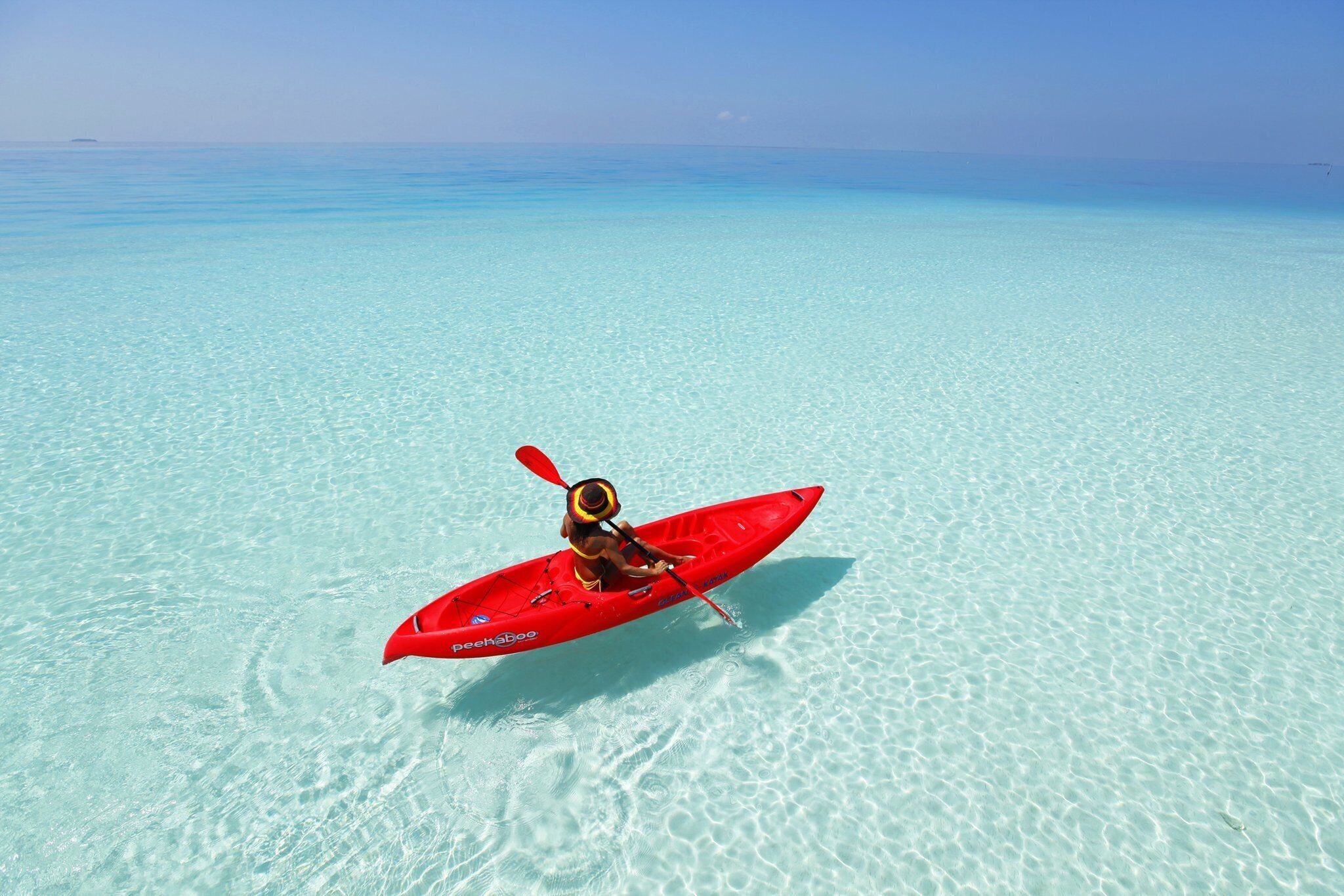 Un kayak rojo sobre aguas turquesas transparentes.