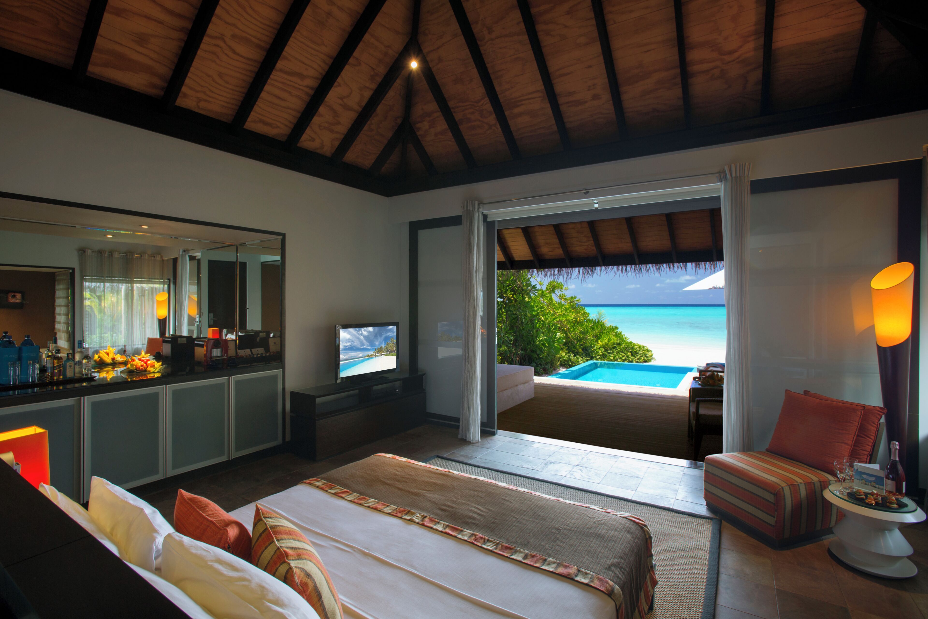 Ein Schlafzimmer mit Bett, Fernseher, Schreibtisch und Blick aufs Meer.