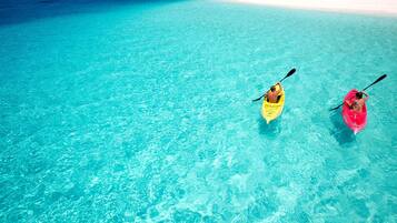 Dois caiaques em um mar azul-turquesa límpido, com uma praia de areia branca ao fundo.