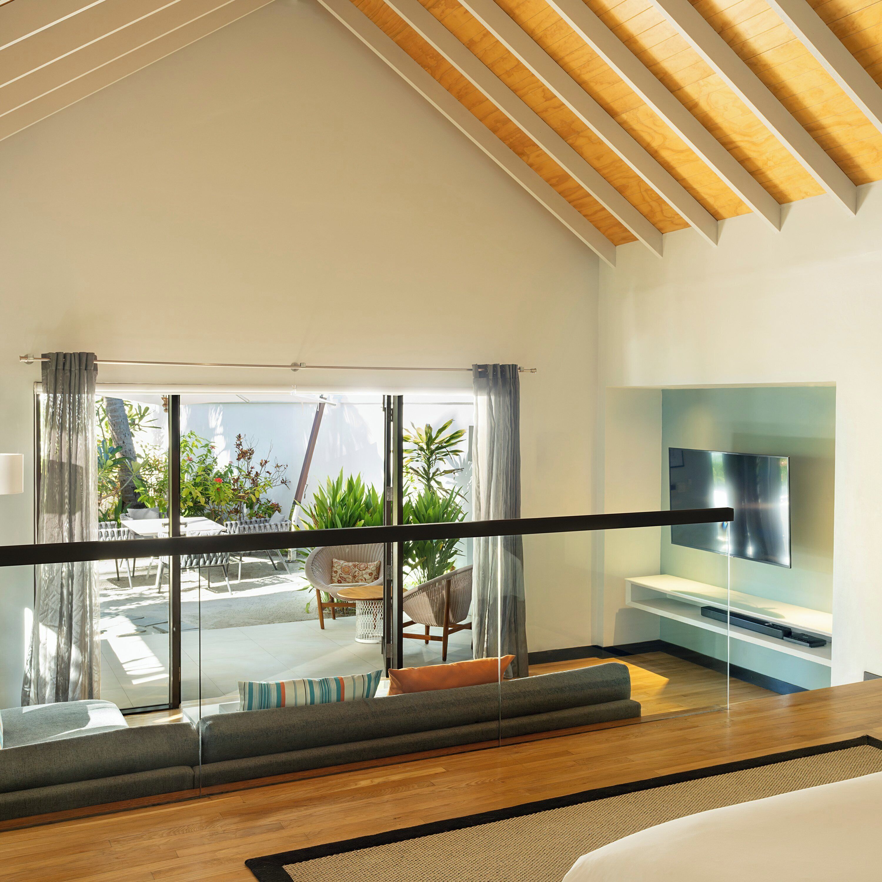Una habitación de hotel moderna con balcón, televisor de pantalla plana y una zona de estar con sofá y sillones.