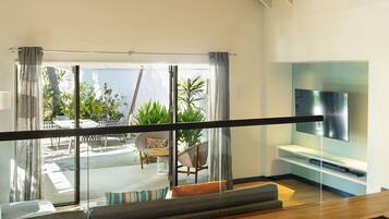 Una habitación de hotel moderna con balcón, televisor de pantalla plana y una zona de estar con sofá y sillones.