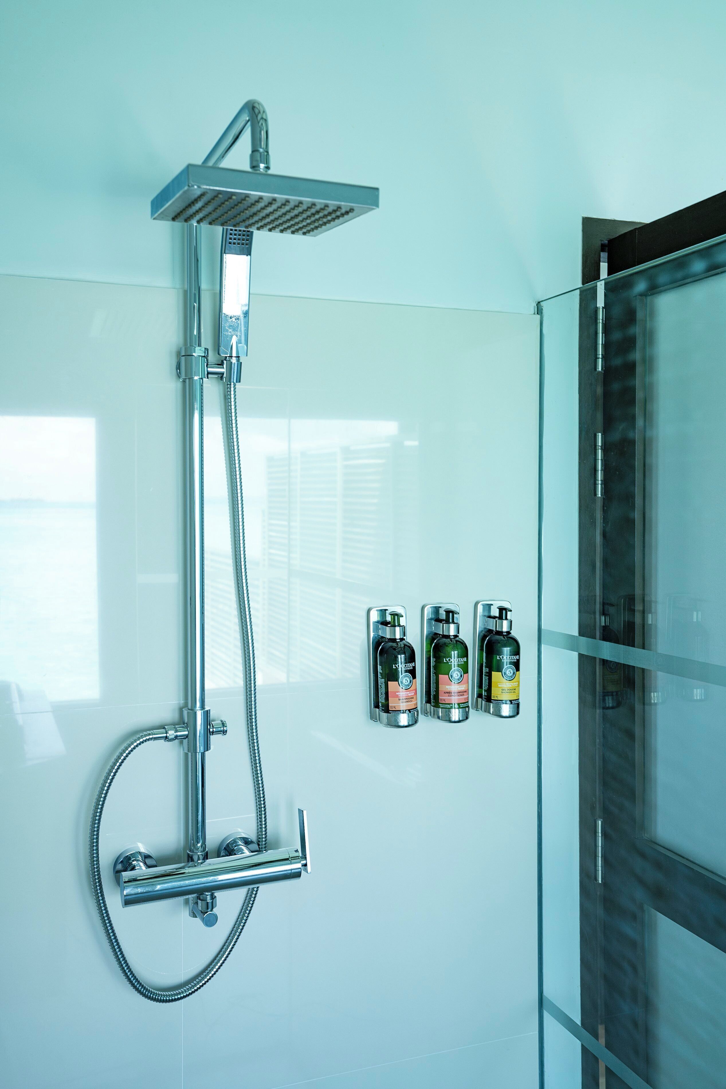 Ein modernes Badezimmer mit Dusche, Glasabtrennung und drei Toilettenartikeln an der Wand.