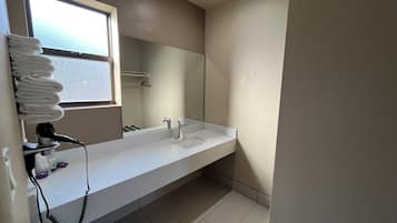 A bathroom with a white sink, a mirror, and a window.