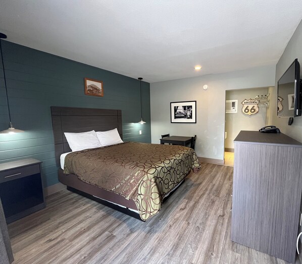A hotel room with a bed, bedside tables, a desk, a mirror, and a wall clock.