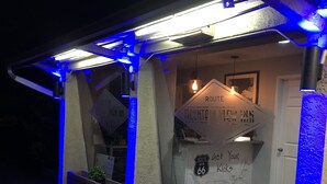 A covered porch with blue lighting, signs indicating 'Route 66' and 'View Inn', and a 'Get Your Kicks' sign. - Mountain View Inn (Flagstaff)