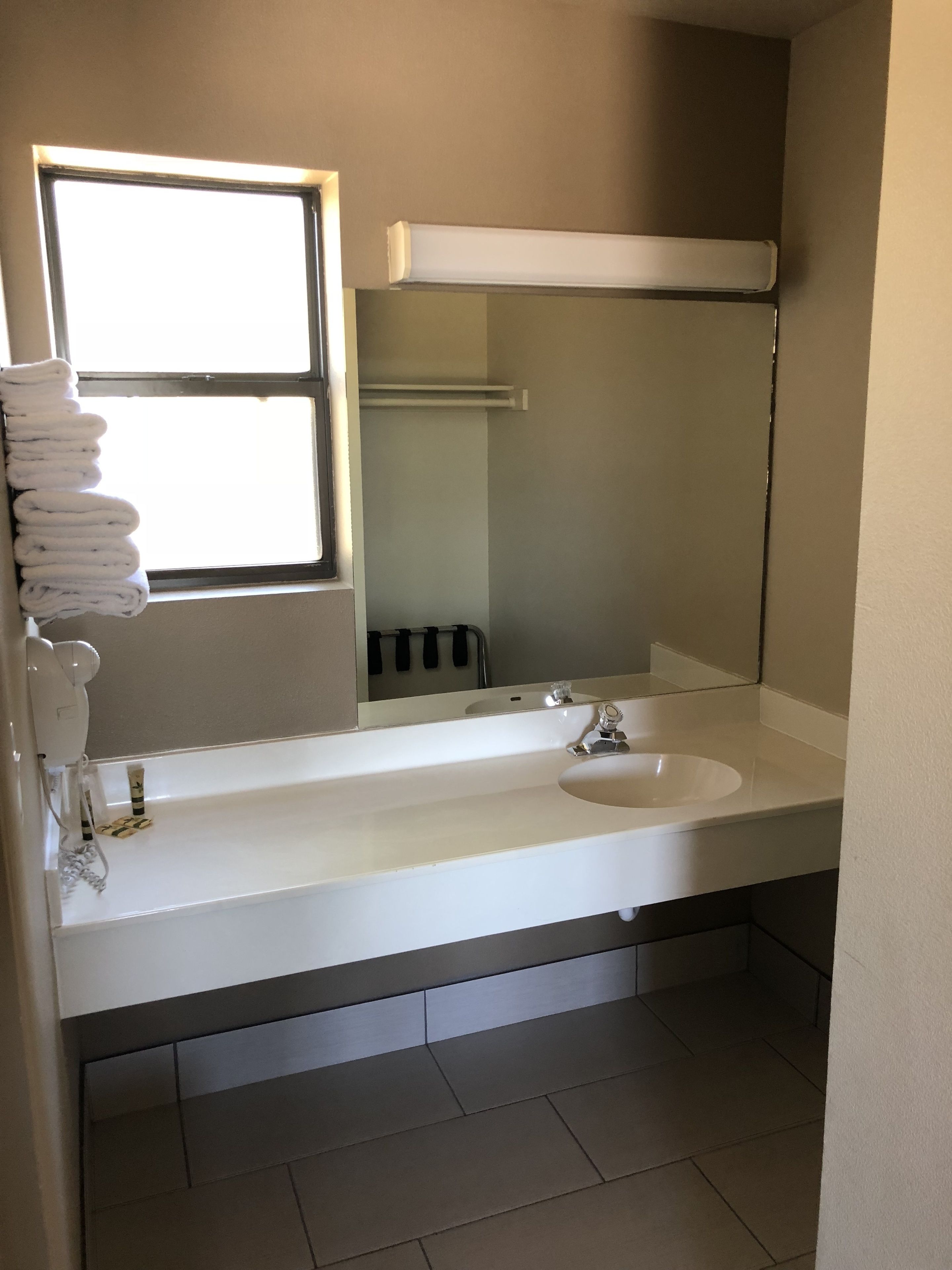 A bathroom with a white sink, a mirror, and a towel rack.