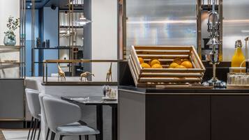 A modern kitchen with a central island, a dining area with chairs, and a view of the kitchen through a glass partition.