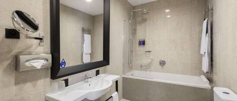 Un baño moderno con un espejo grande, dos lavamanos, una bañera y un inodoro.