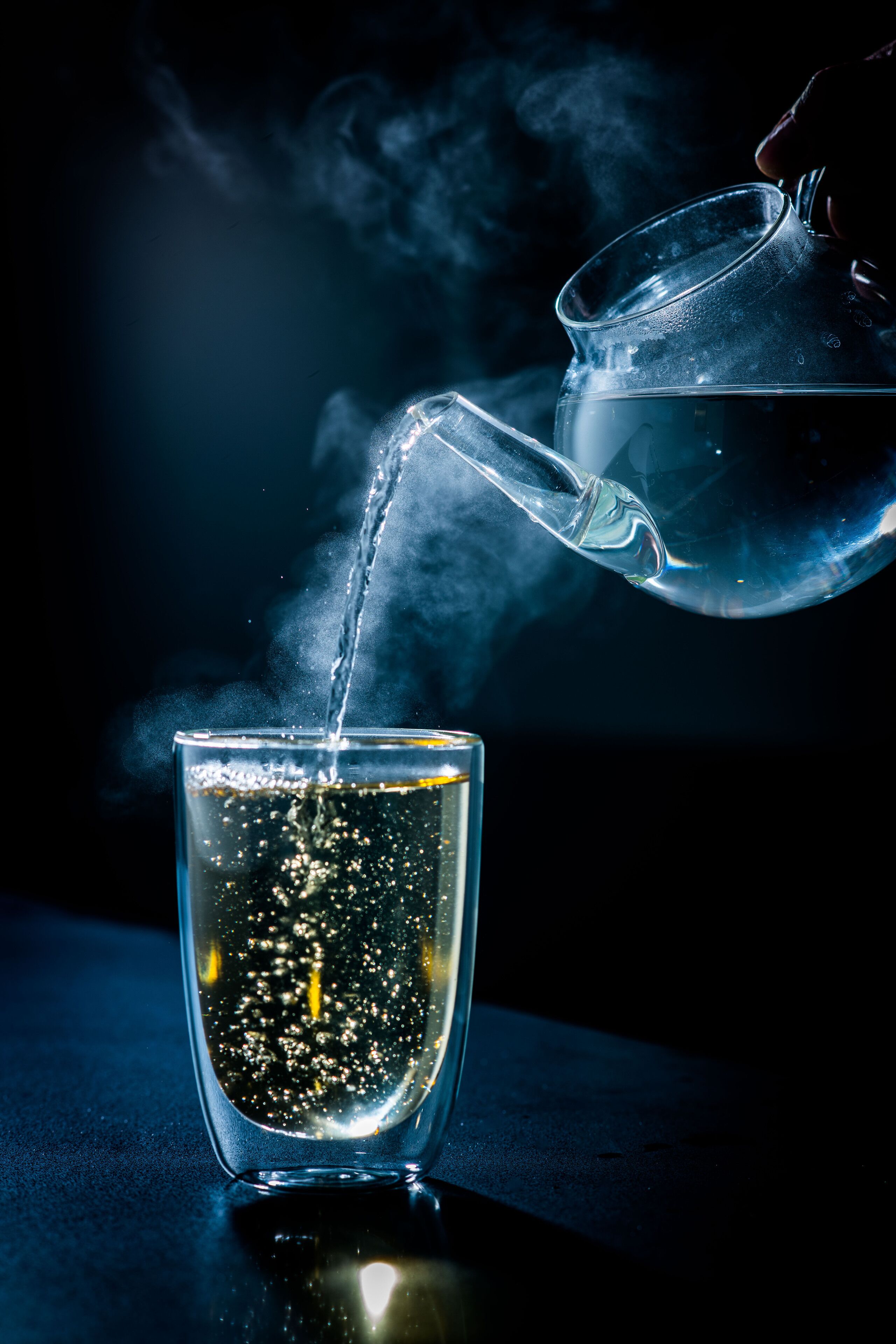 Un bicchiere trasparente viene riempito con un liquido limpido, probabilmente acqua, da cui si alza del vapore.