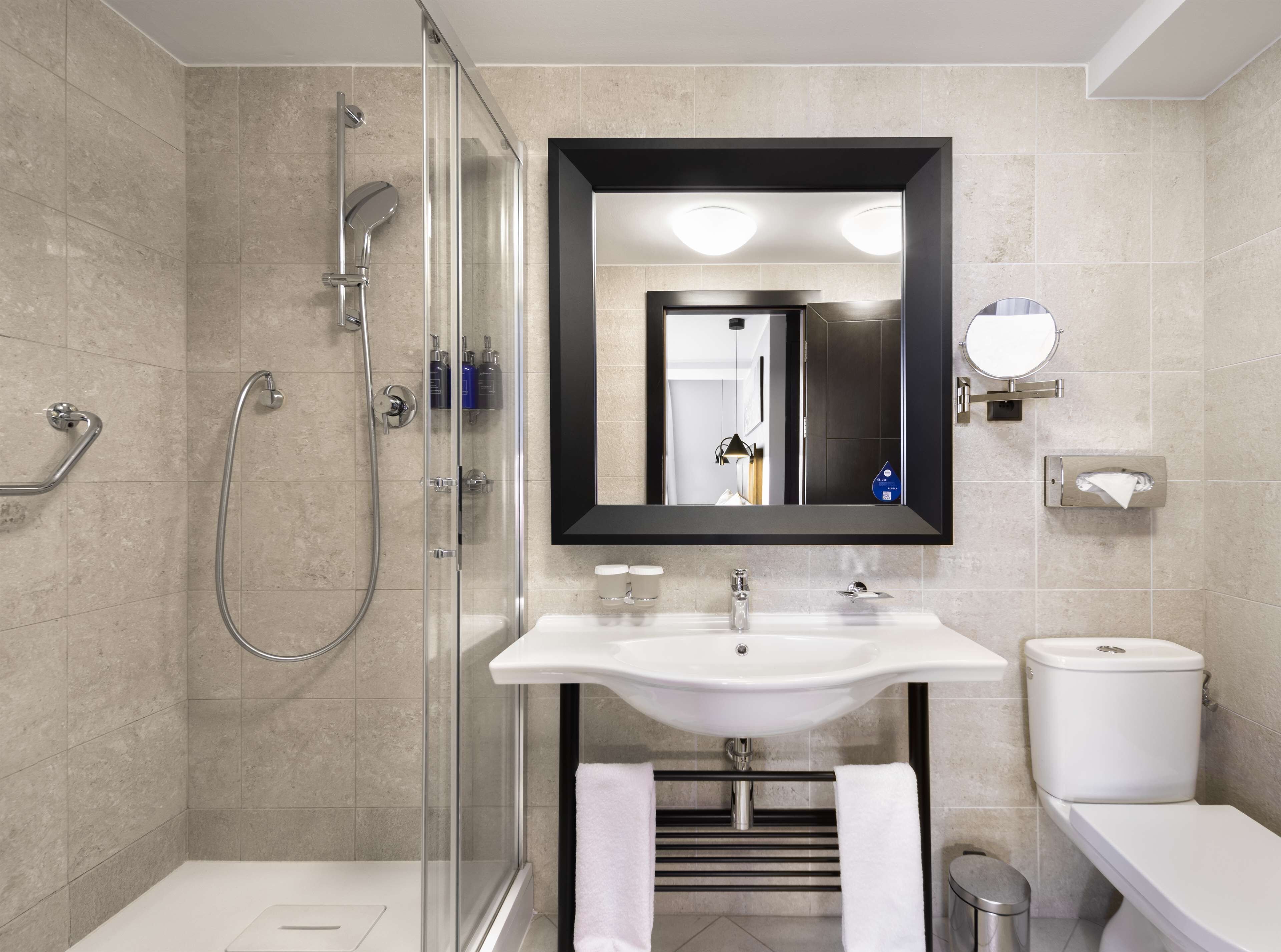 A modern bathroom with a glass-enclosed shower, a white sink, and a toilet.