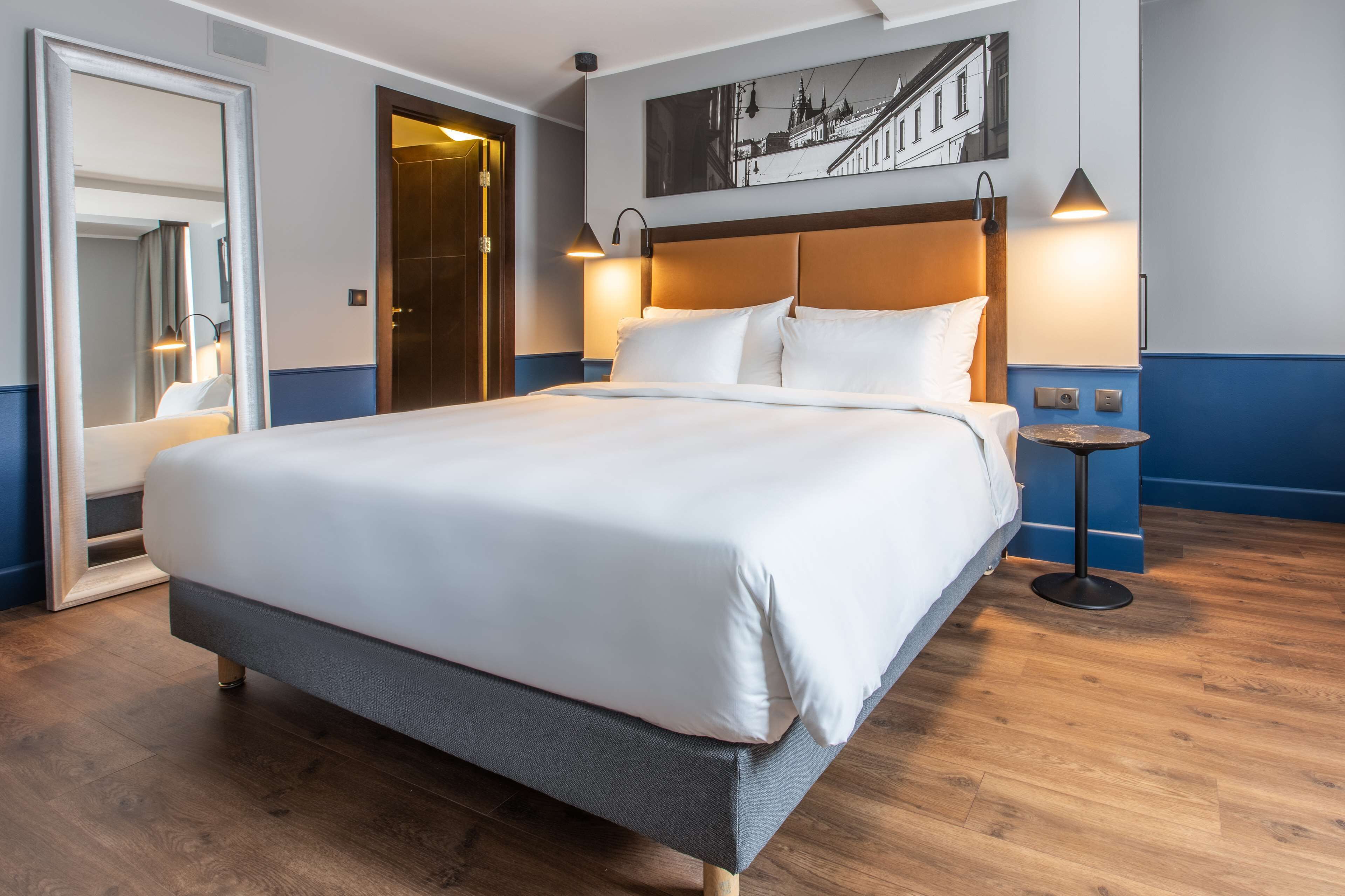 A neatly made bed with white linens in a hotel room.