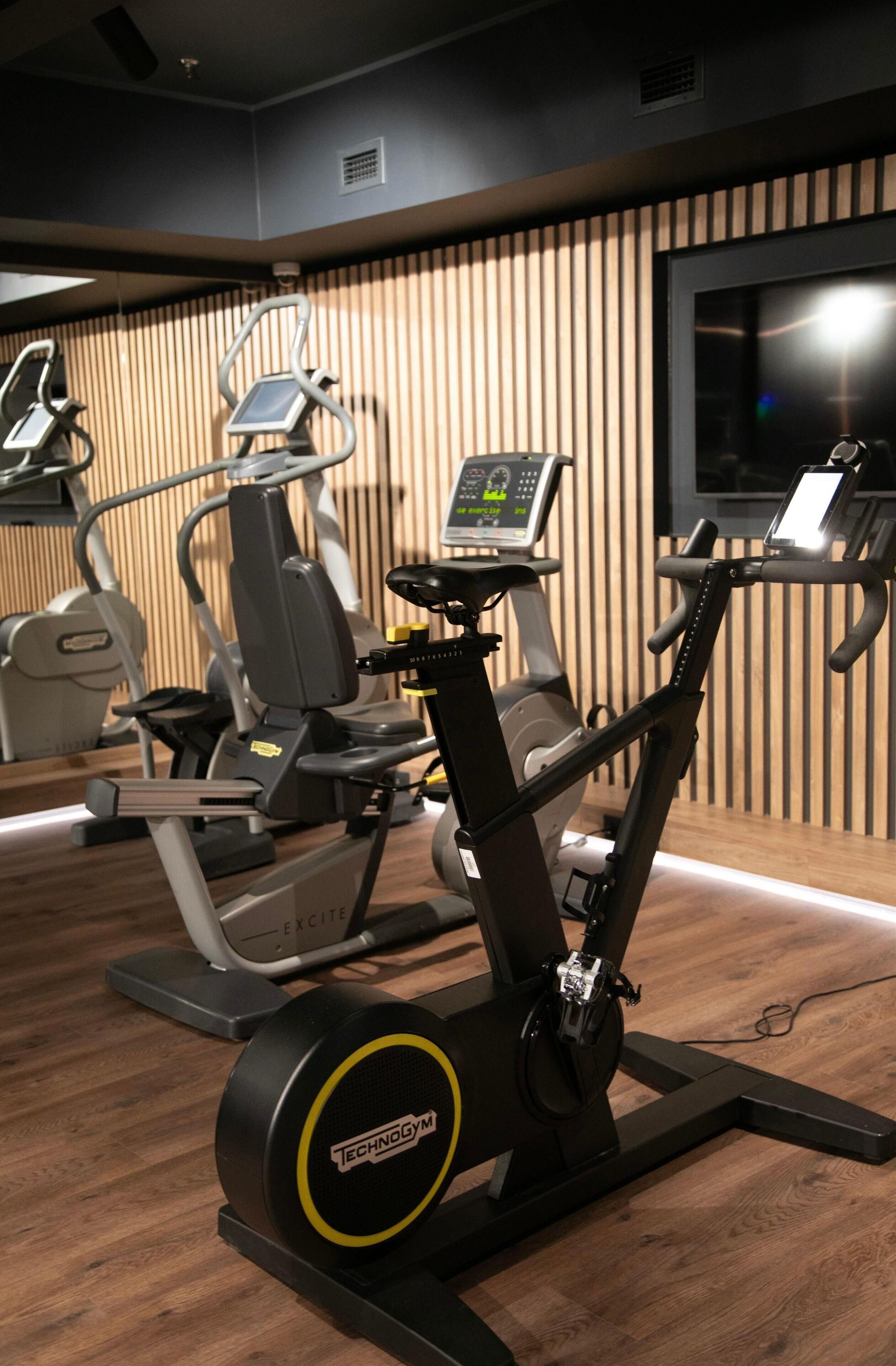 A gym with a stationary bike, elliptical, and weight machine.