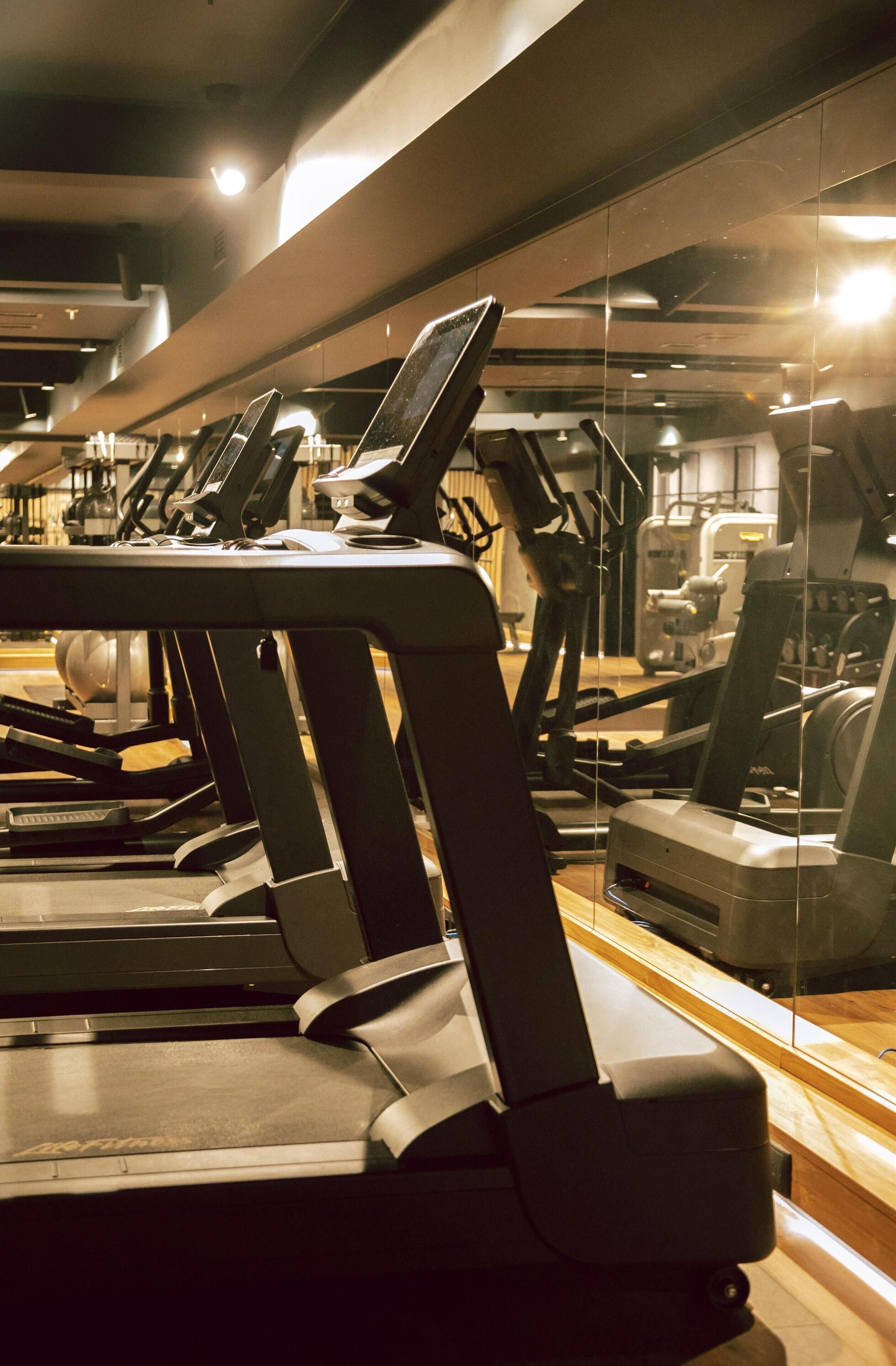 Ein Fitnessstudio mit mehreren Laufbändern und Trainingsgeräten.