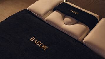 A plush, dark-colored sofa with the word "BABOR" embroidered in gold.