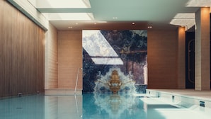 Una piscina interior moderna con un gran mural, paredes de madera y tragaluces.