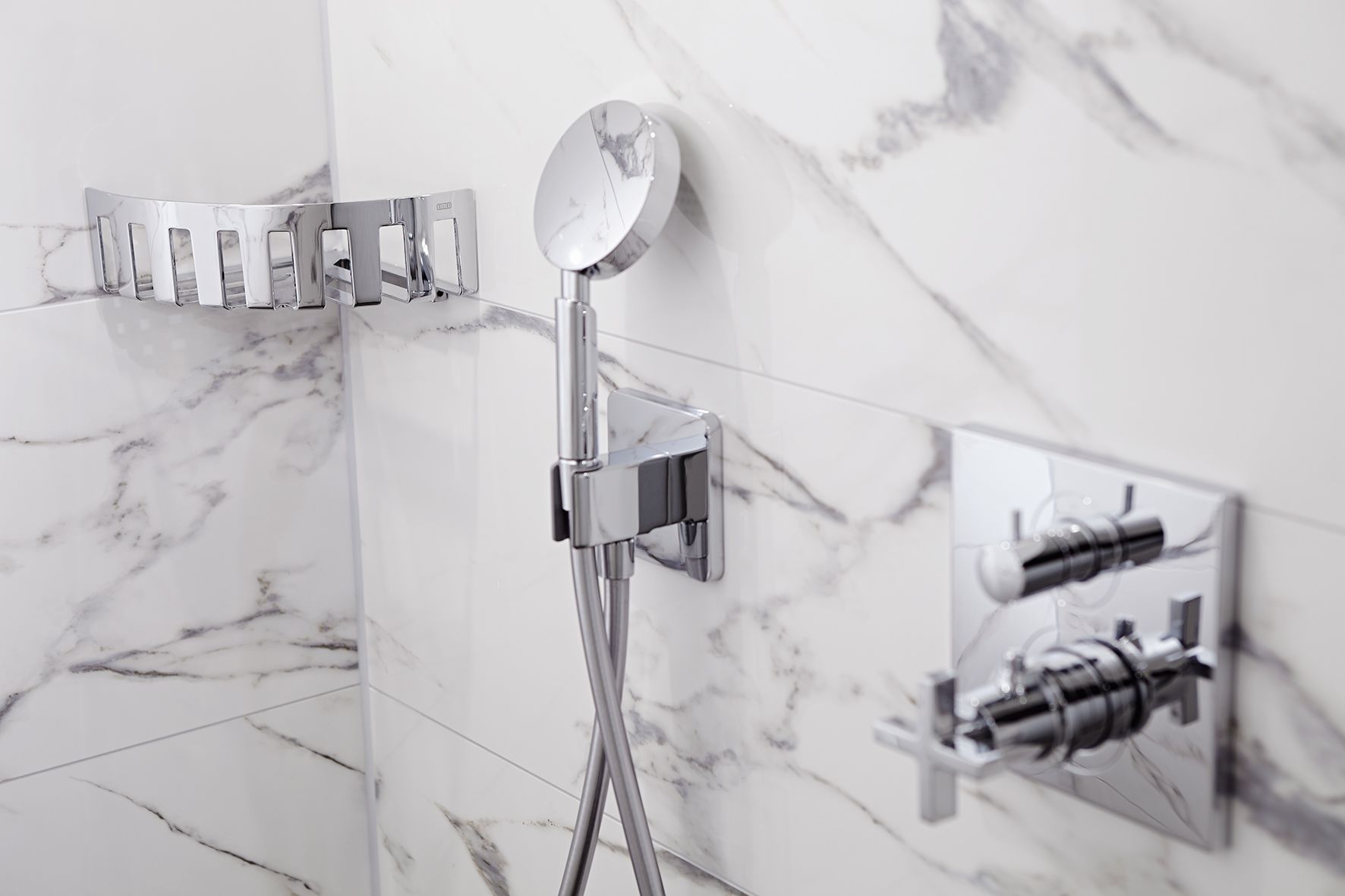 Een moderne badkamer met een marmeren wand, een handdouche en een wandmengkraan.