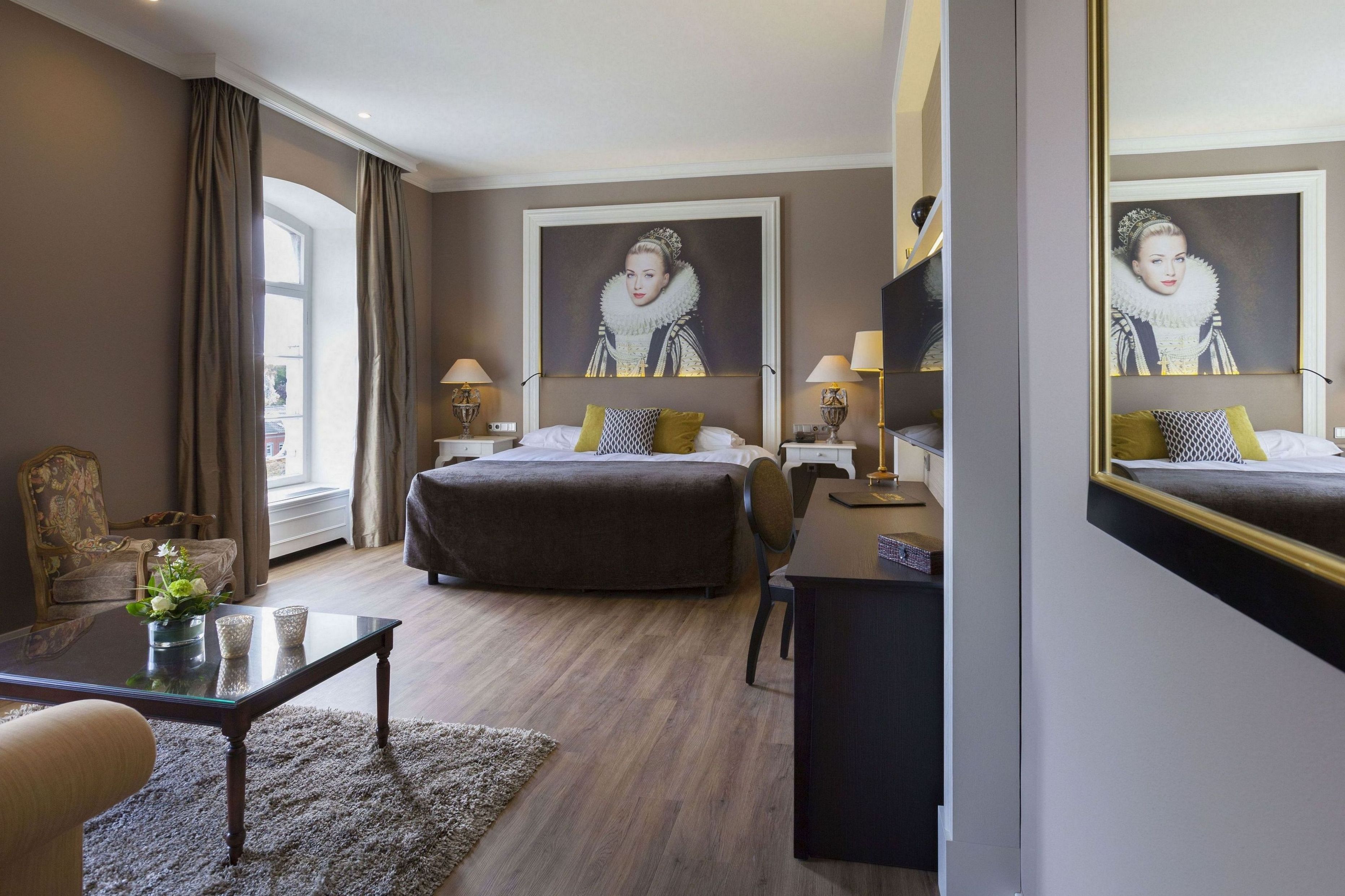 Een hotelkamer met een groot bed, een bureau, een stoel en een grote spiegel.