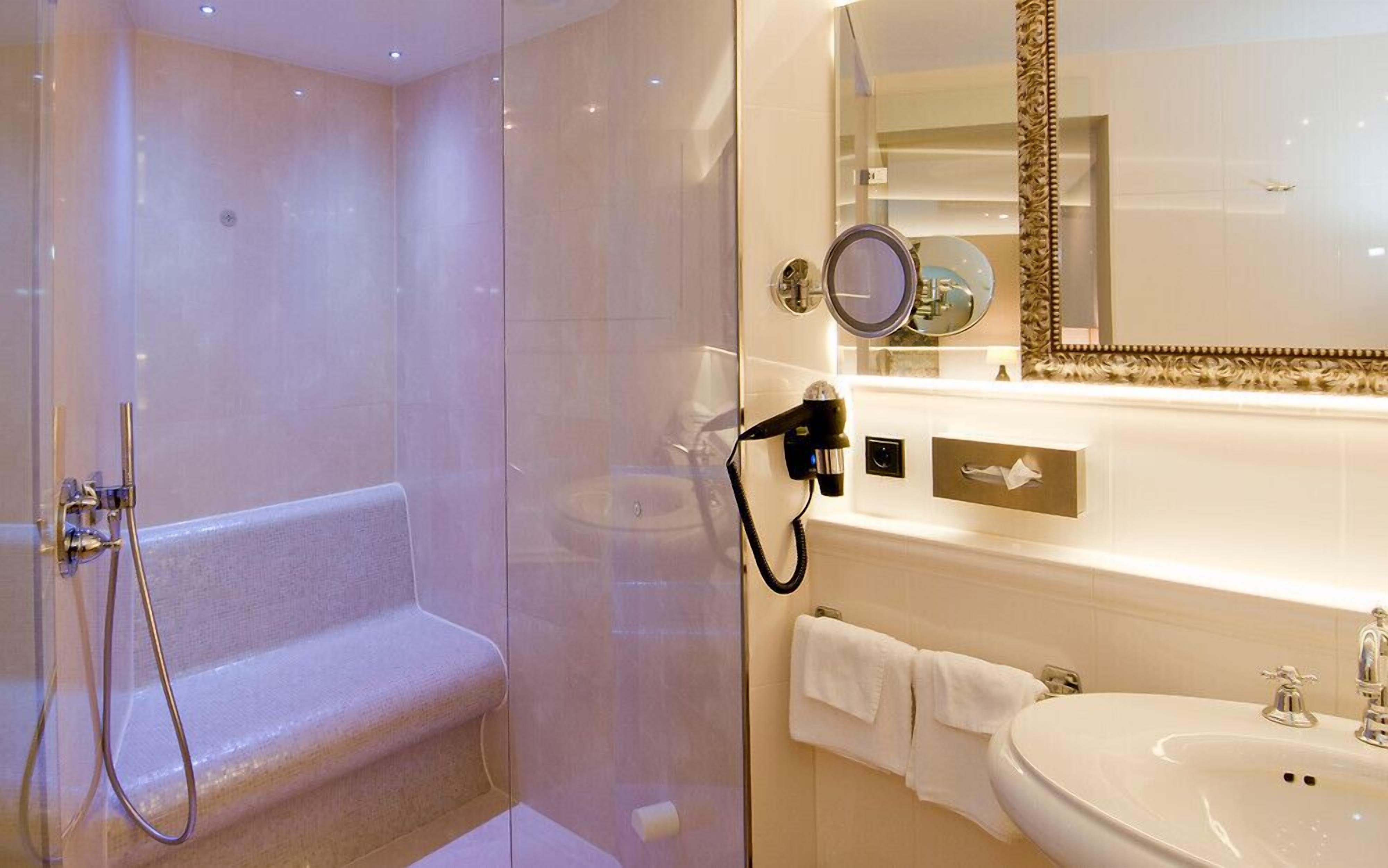 A modern bathroom with a glass-enclosed shower, a vanity with a sink, and a large mirror.