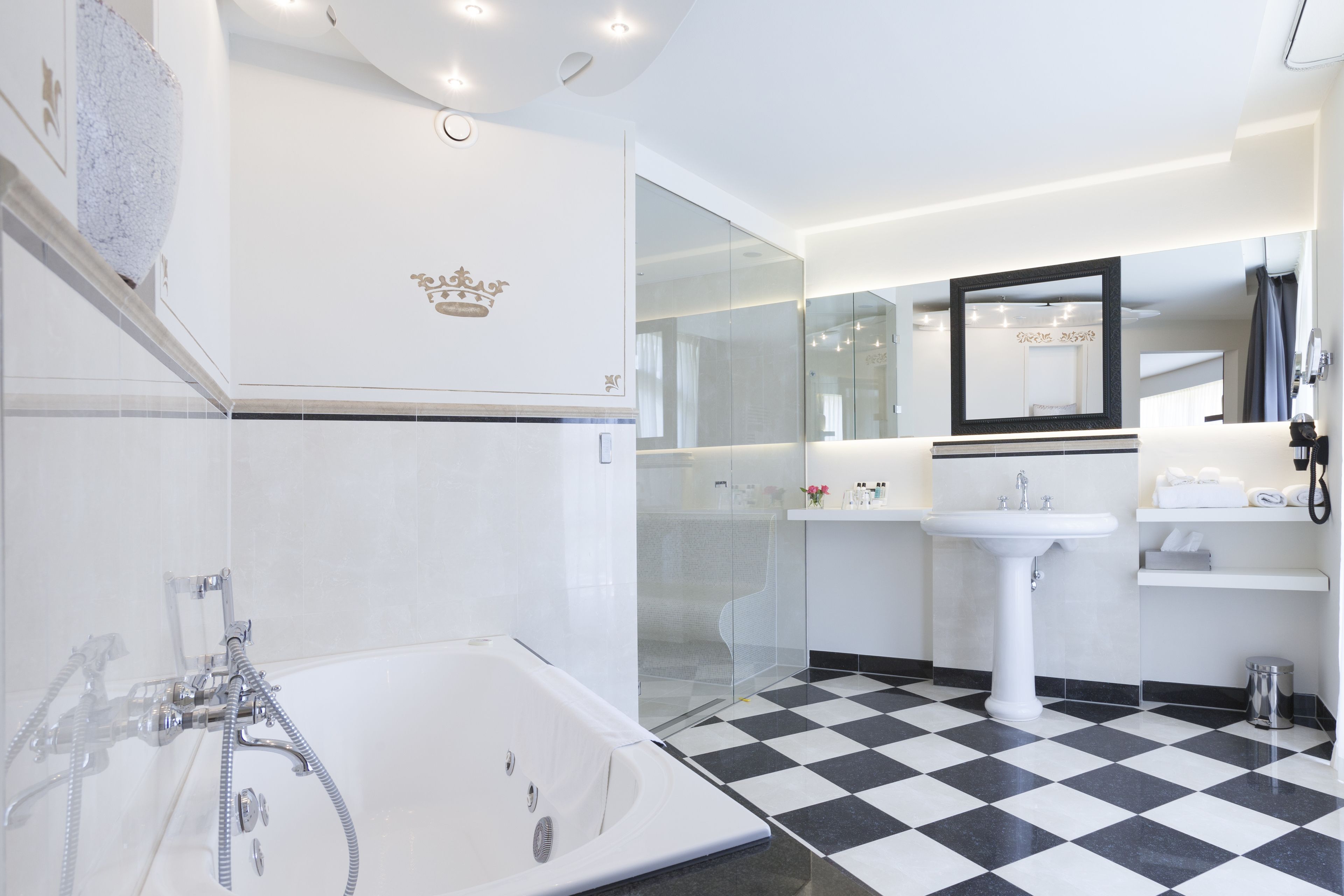 Ein modernes Badezimmer mit einer großen Badewanne, einer gläsernen Dusche, einem weißen Waschbecken und einem Spiegel darüber.