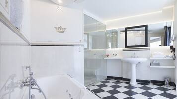 Ein modernes Badezimmer mit einer großen Badewanne, einer gläsernen Dusche, einem weißen Waschbecken und einem Spiegel darüber.