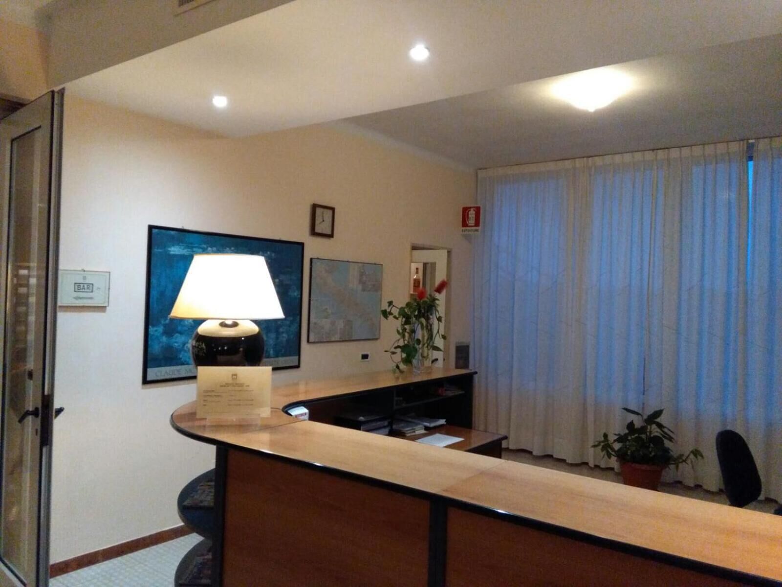 Un mostrador de recepción con una lámpara, un reloj y un cuadro en la pared.