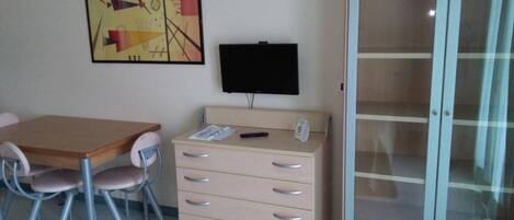 A room with a wooden desk, a chair, a filing cabinet, and a television.