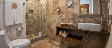 A bathroom with a white toilet, a shower with a glass door, a sink with a mirror, and a tiled floor.