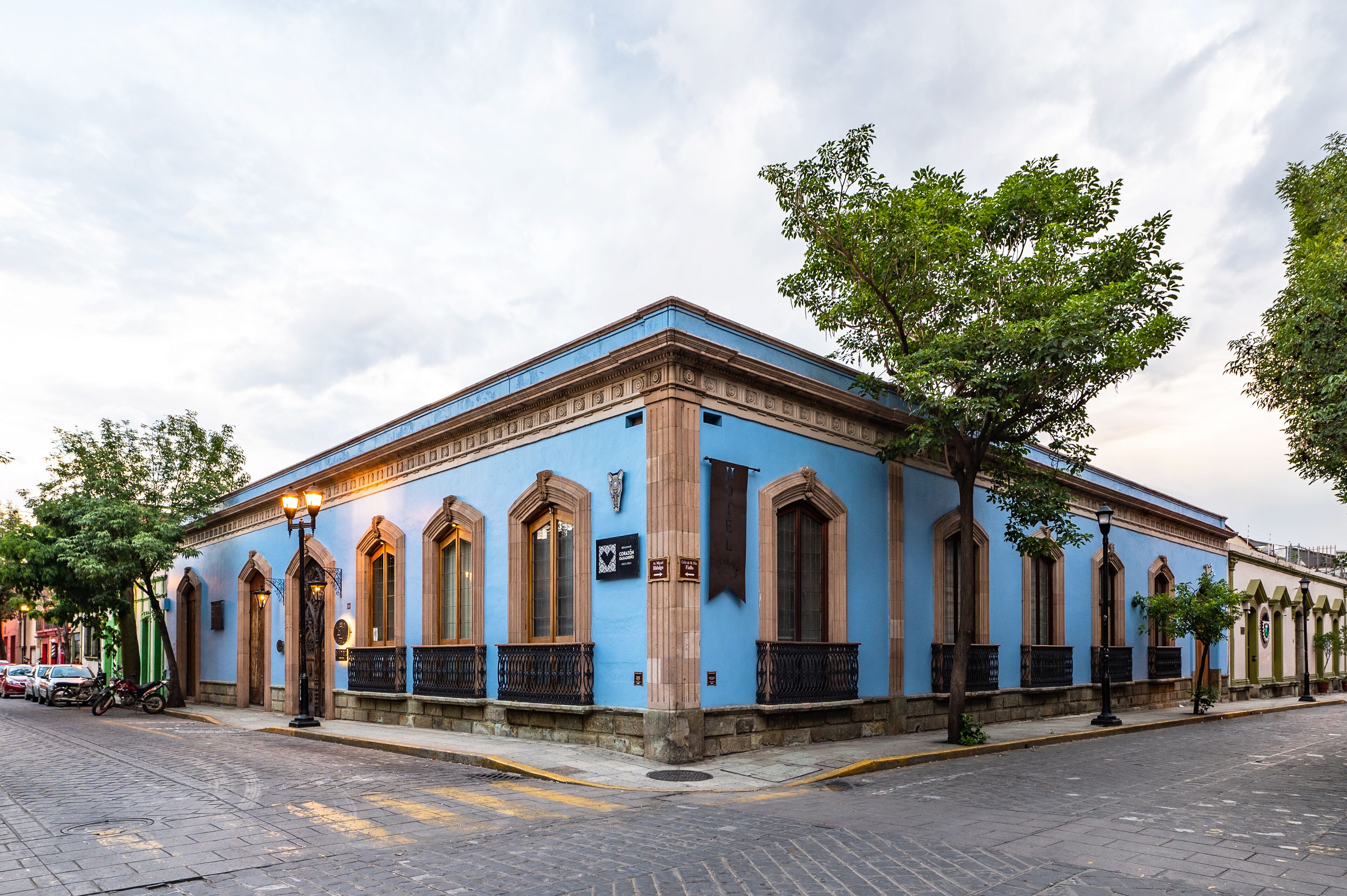 A historic building with arched windows and a blue facade, located on a cobblestone street.