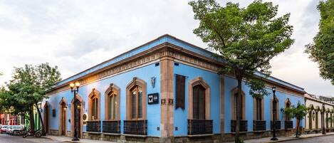 A historic building with arched windows and a blue facade, located on a cobblestone street.