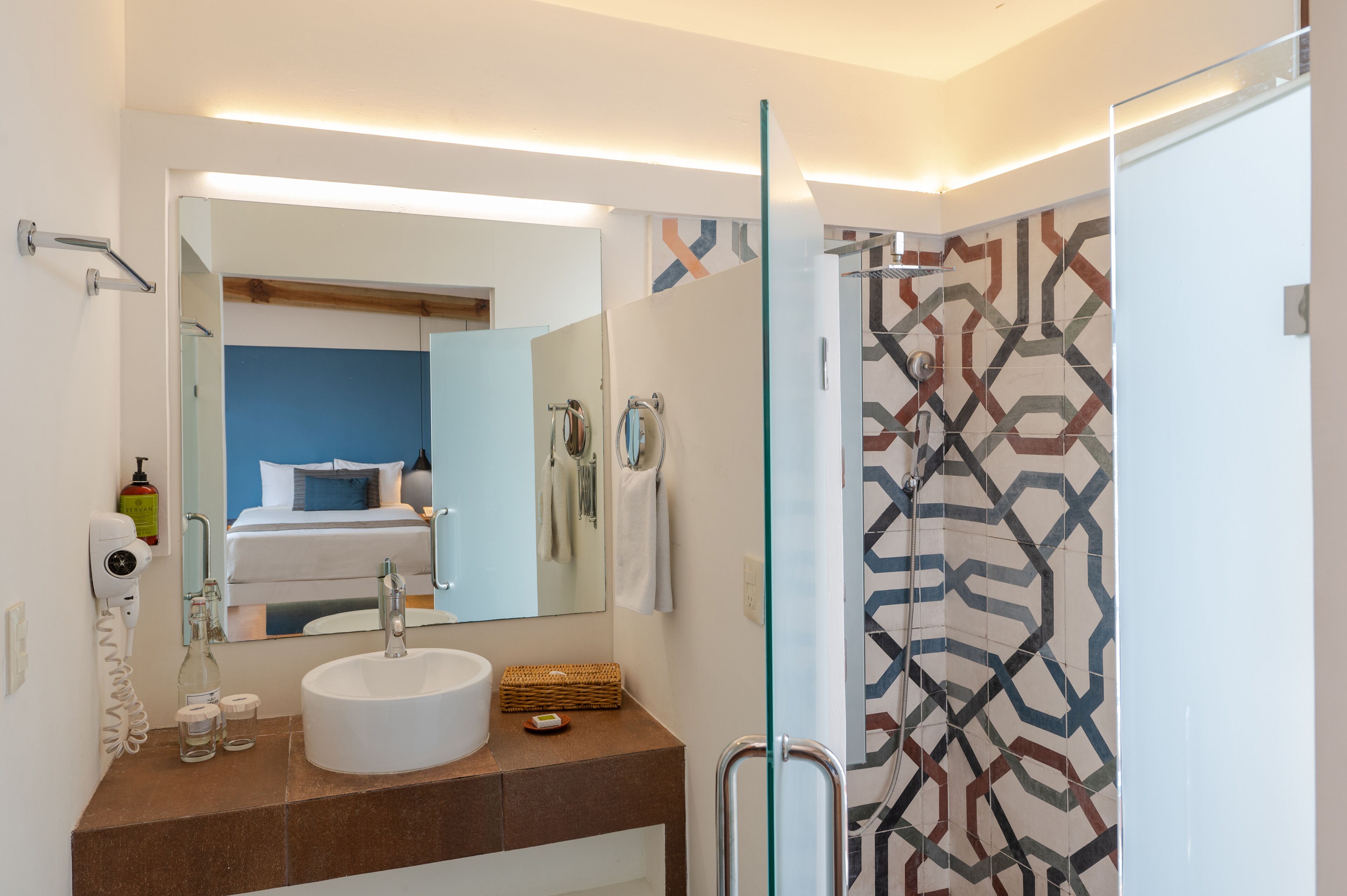 A modern bathroom with a large mirror, a sink, and a shower area.