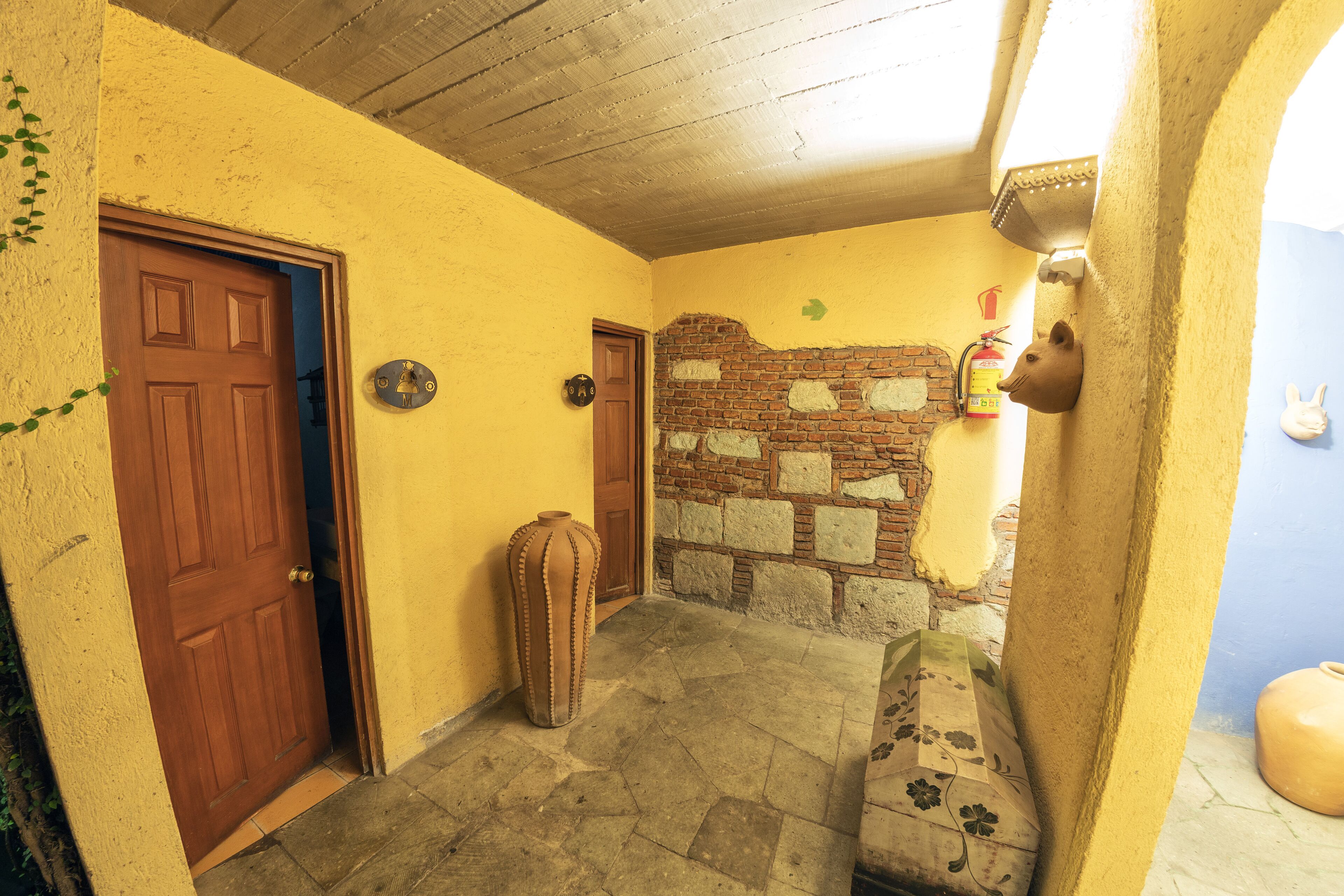 A hallway with a wooden door, a stone bench, and a brick wall.