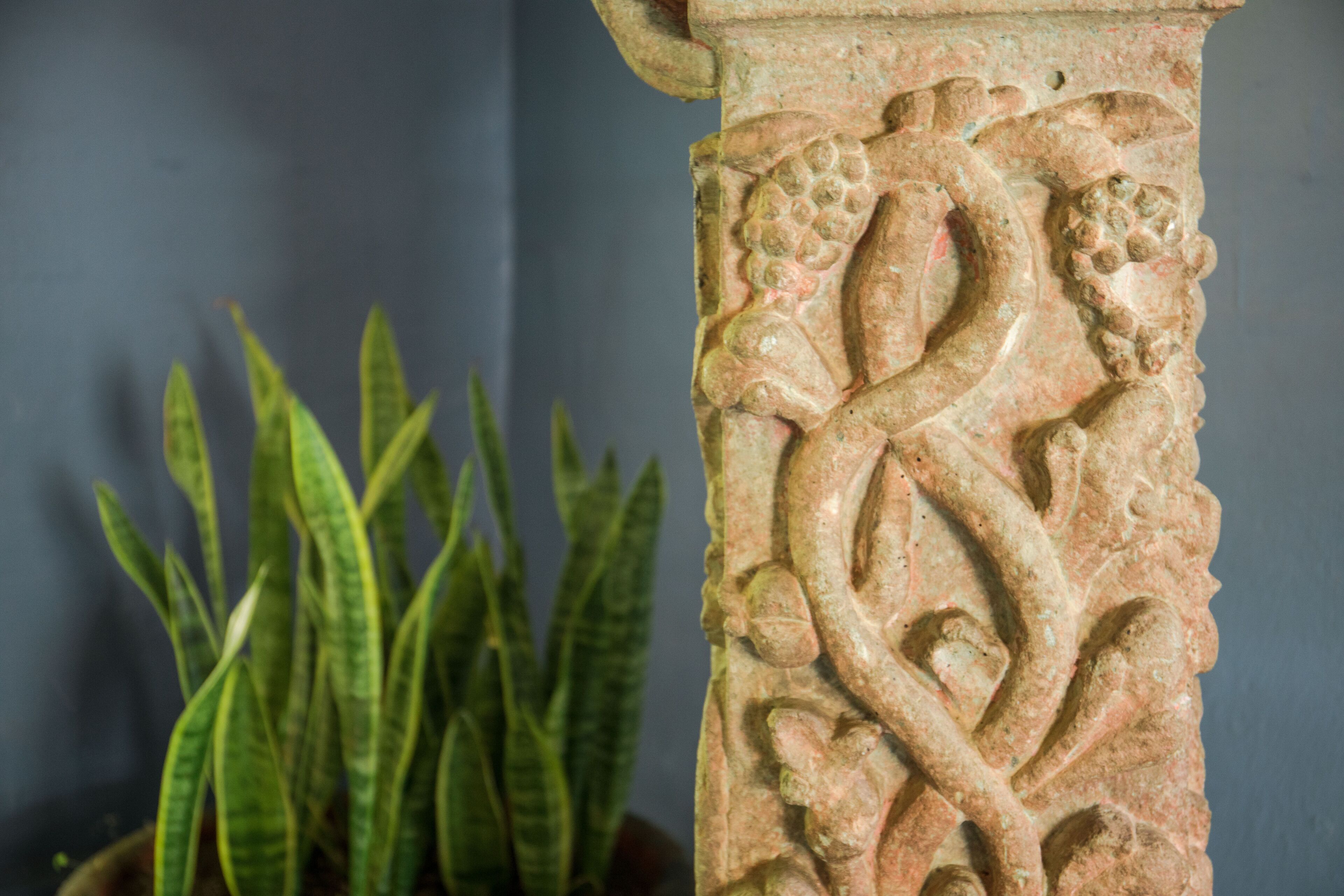 Primer pla d'una columna de pedra amb detalls esculpits intricats, incloent una serp i motius florals.