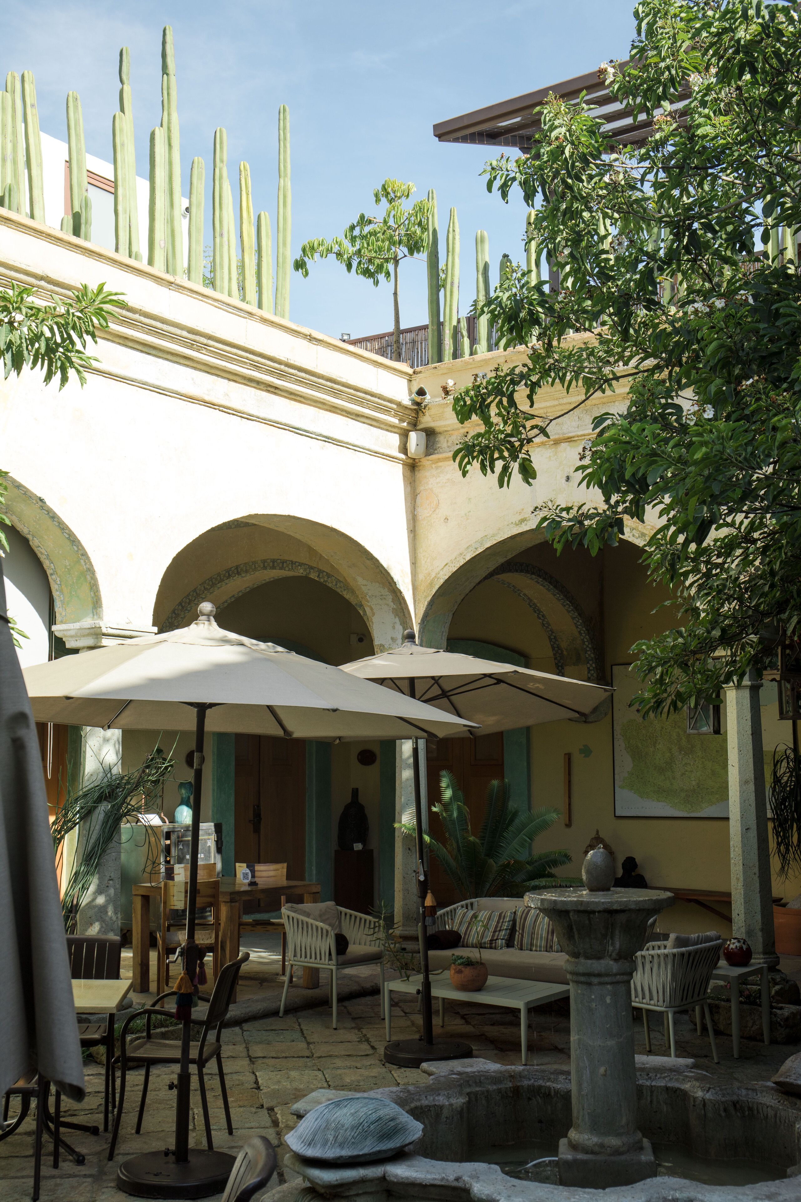 Un patio al aire libre con mesa y sillas, una fuente y cactus.