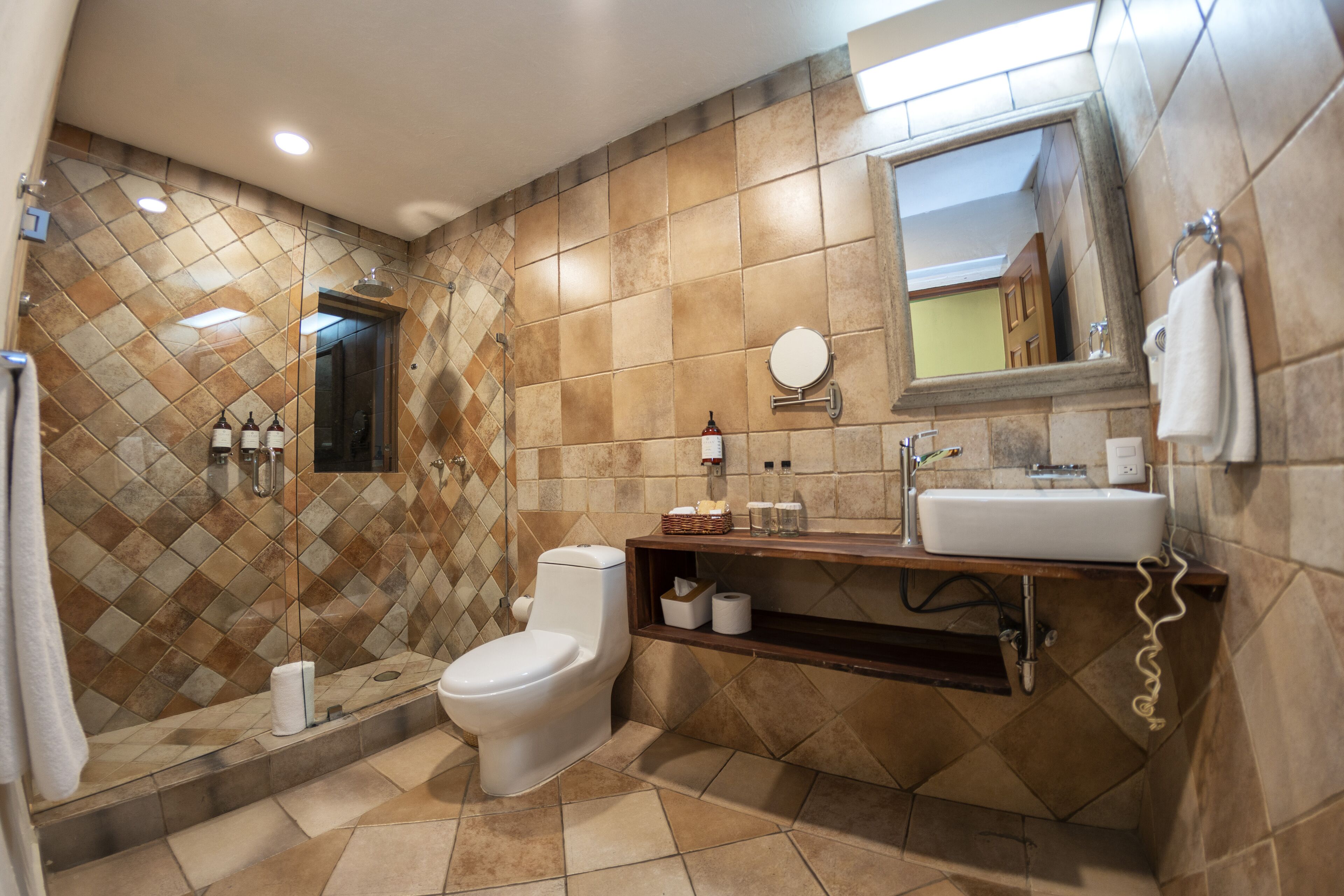 Une salle de bain équipée d’une douche, de toilettes, d’un lavabo et d’un miroir.