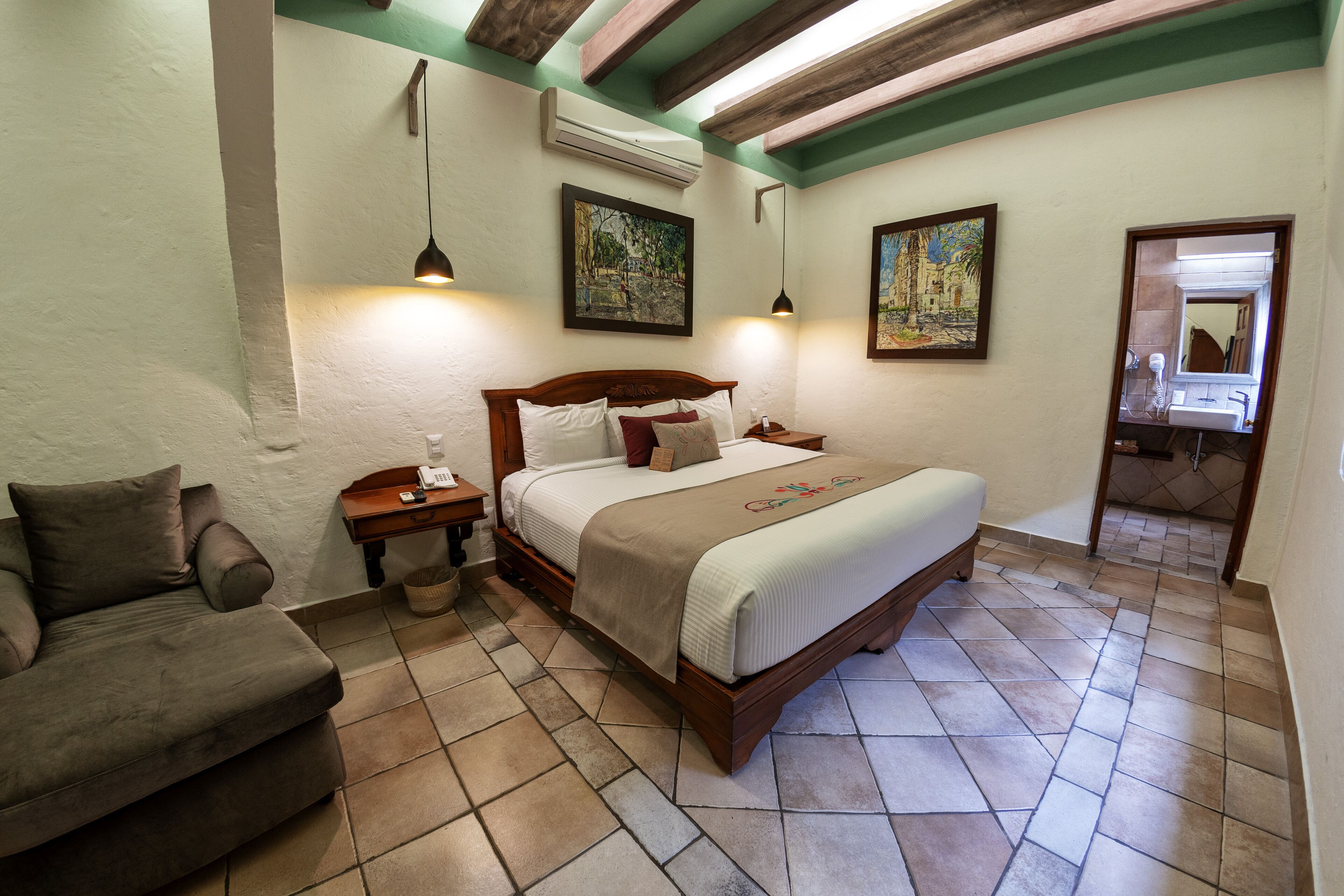 A bedroom with a bed, a nightstand, a sofa, and a mirror.