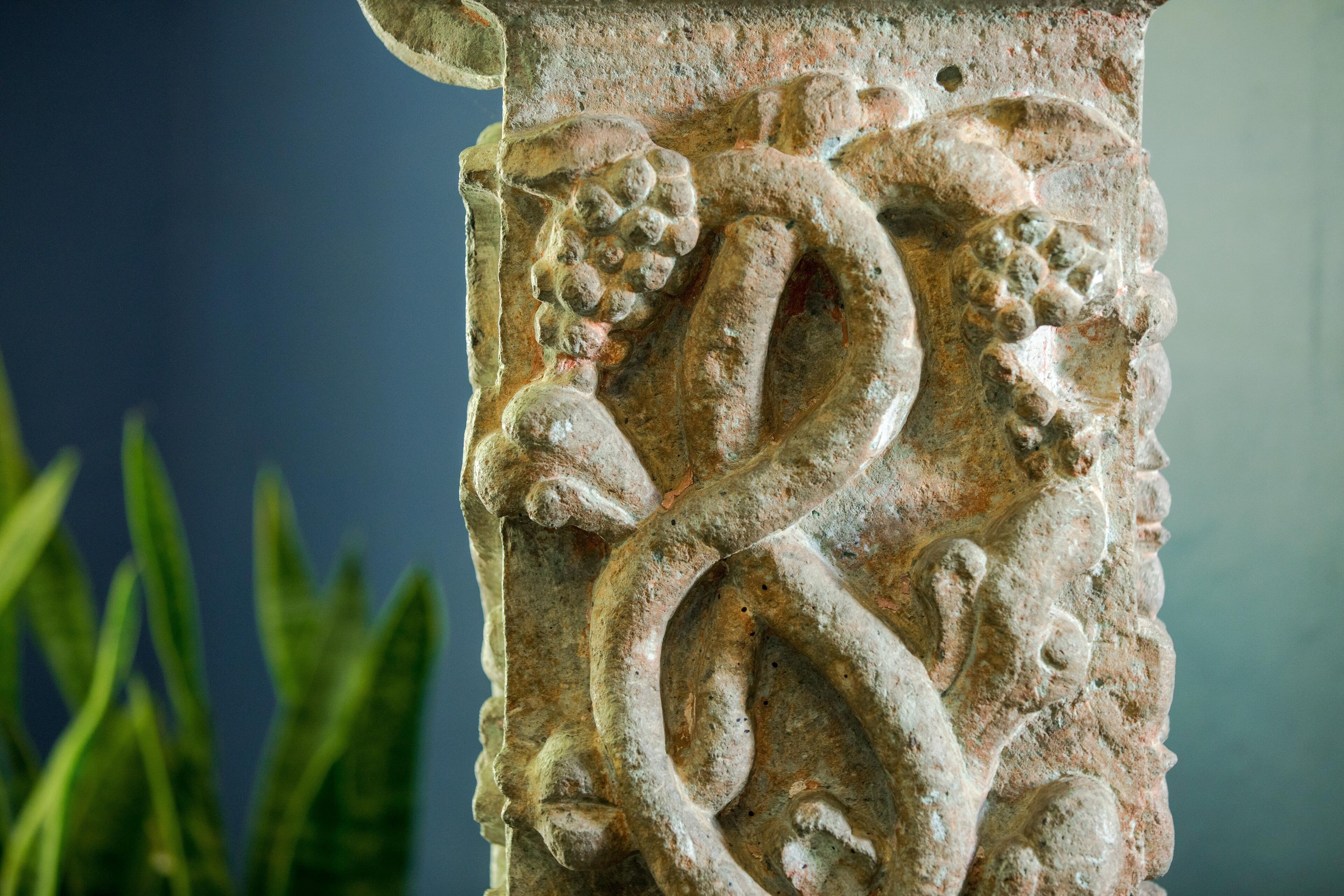 A close-up of a stone carving with a serpent and grapes, likely part of a historical monument or building.