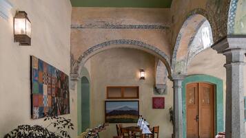 A courtyard with a bicycle, a table with chairs, and a large painting on the wall.