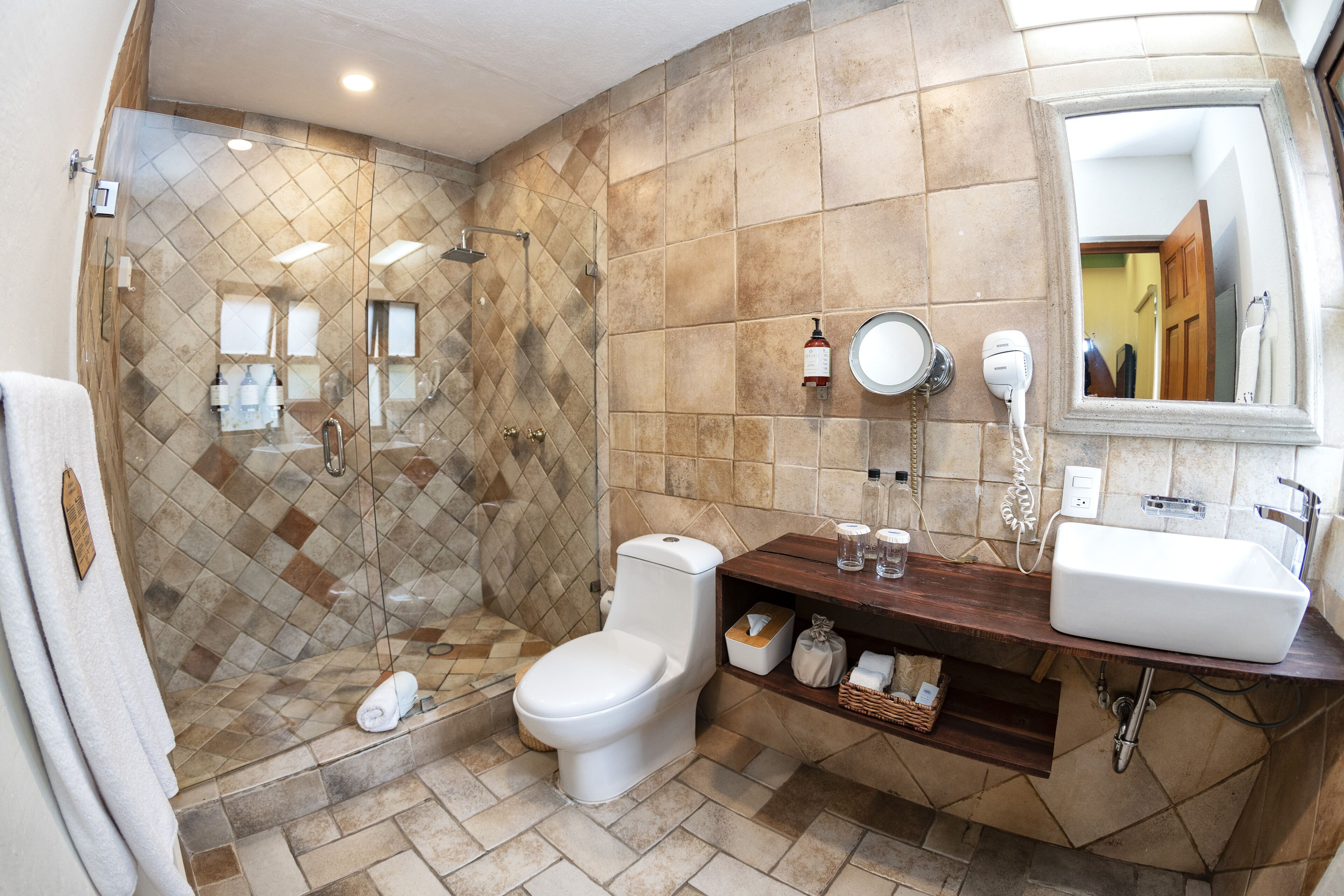 Un baño con ducha, inodoro y tocador con lavabo.