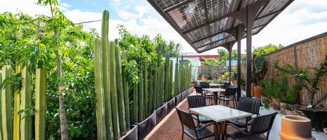 An outdoor patio with brick flooring, cactus plants, and a table with chairs.