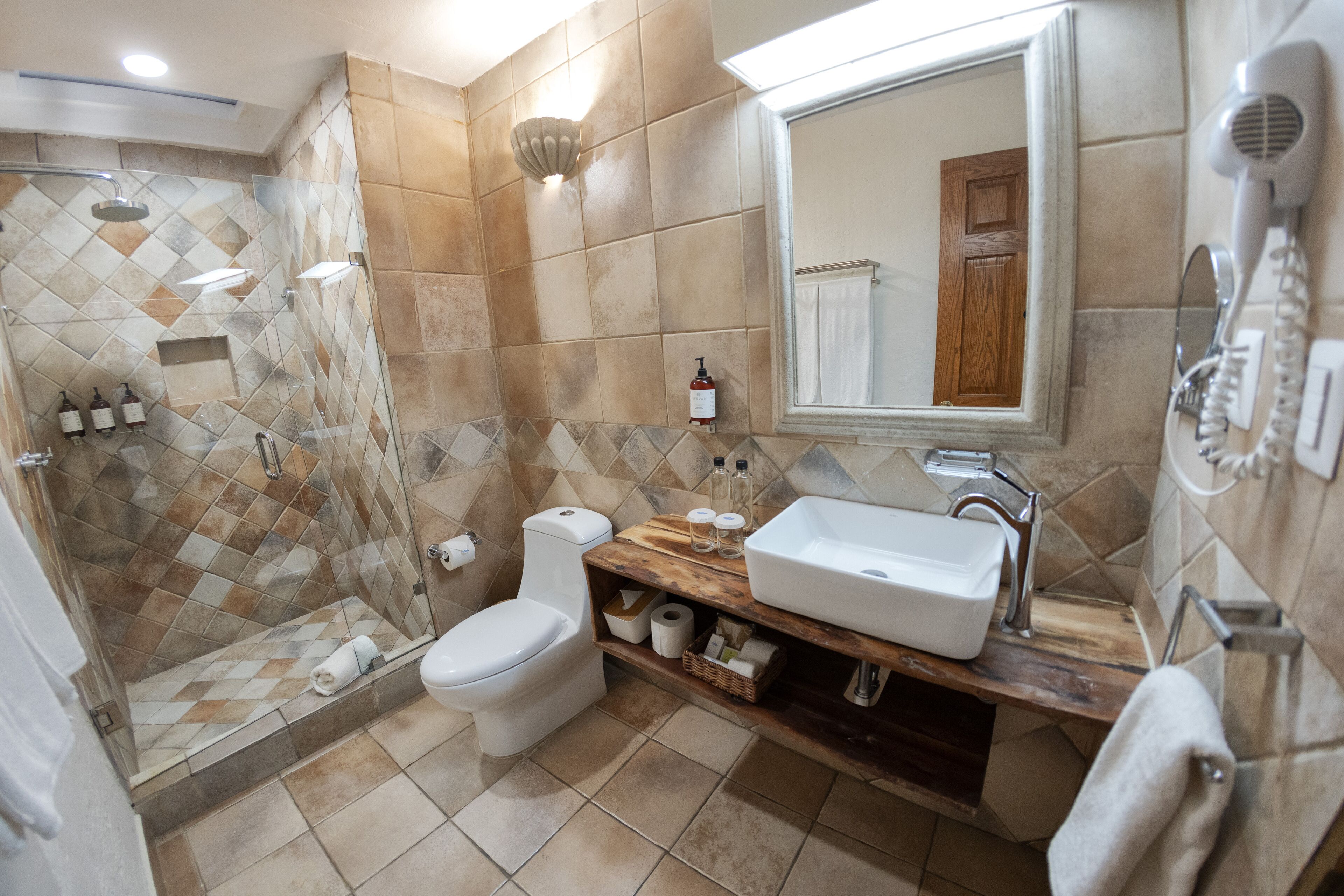 Un baño con ducha, inodoro, lavabo y espejo.