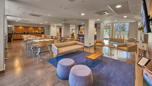 Eine moderne Hotelhalle mit Empfangsbereich, Essbereich und einem Spielbereich für Kinder.