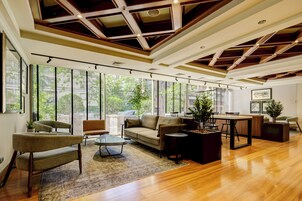 Un espacio habitable amplio con techo de madera, ventanas grandes y muebles modernos.
