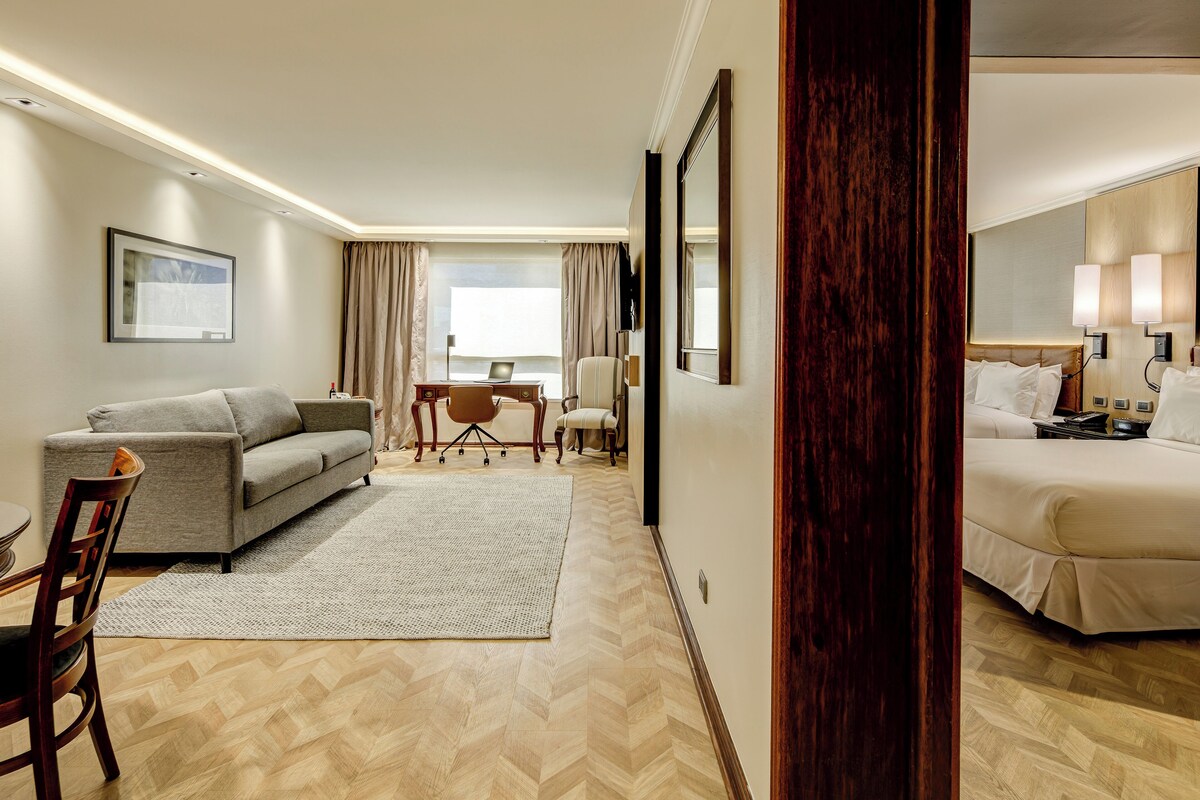 Ein Hotelzimmer mit einer Couch, einem Schreibtisch, einem Sessel und einem Bett.