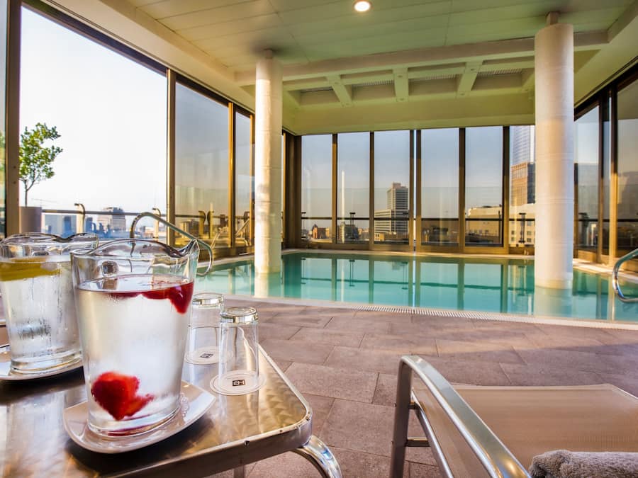 Zona de piscina con mesa, sillones reclinables y vista al horizonte de la ciudad.