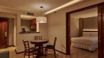 Ein Hotelzimmer mit Bett, Esstisch mit Stühlen, einer Küchenzeile und einem Flur.