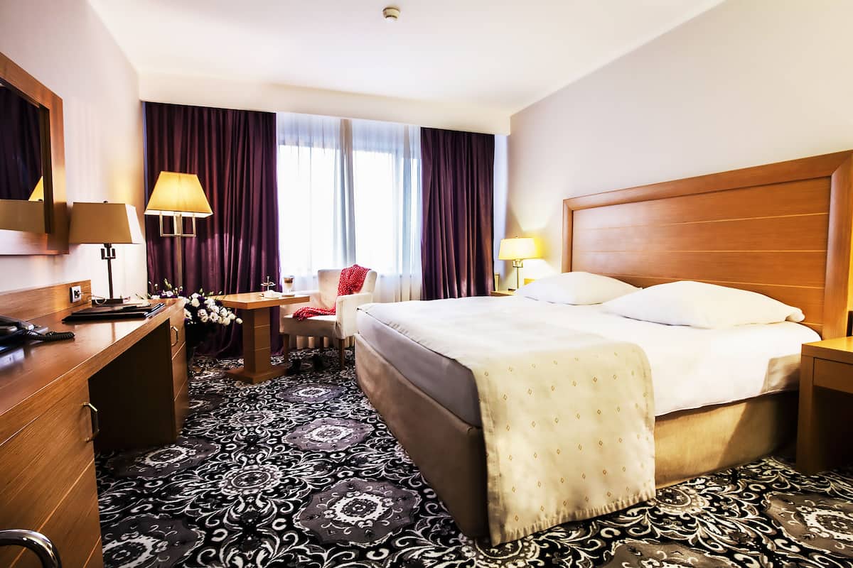 Ein Hotelzimmer mit einem großen Bett, einem Schreibtisch, einem Stuhl und einer Schreibtischlampe.