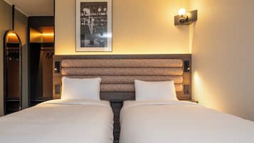 Una camera d'albergo con due letti, un quadro appeso alla parete e un lampadario sopra i letti.